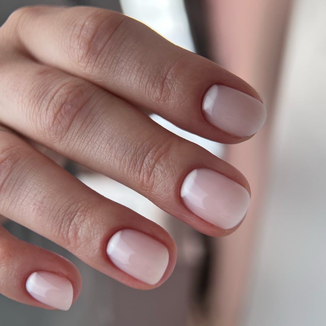 Hand with natural-looking nails created using Paloma Builder Gel (hard gel) in shade G015 Old Money. This semi-transparent nude hard gel provides a subtle, elegant look with a smooth, glossy finish, ideal for a polished, minimalist manicure. The long-lasting formula ensures durability and a flawless appearance.