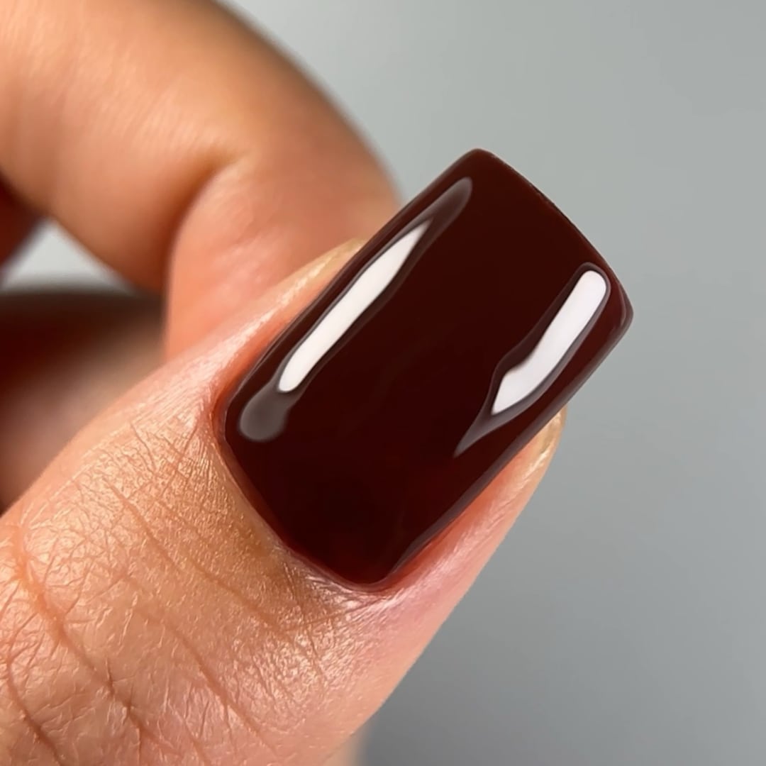 Close-up of a fingernail painted with Paloma's long-lasting, highly-pigmented gel nail polish in shade C011, a rich chocolate brown color. Finished with Paloma Shine Top Coat for a glossy, durable look, perfect for a sophisticated and elegant fall gel manicure.
