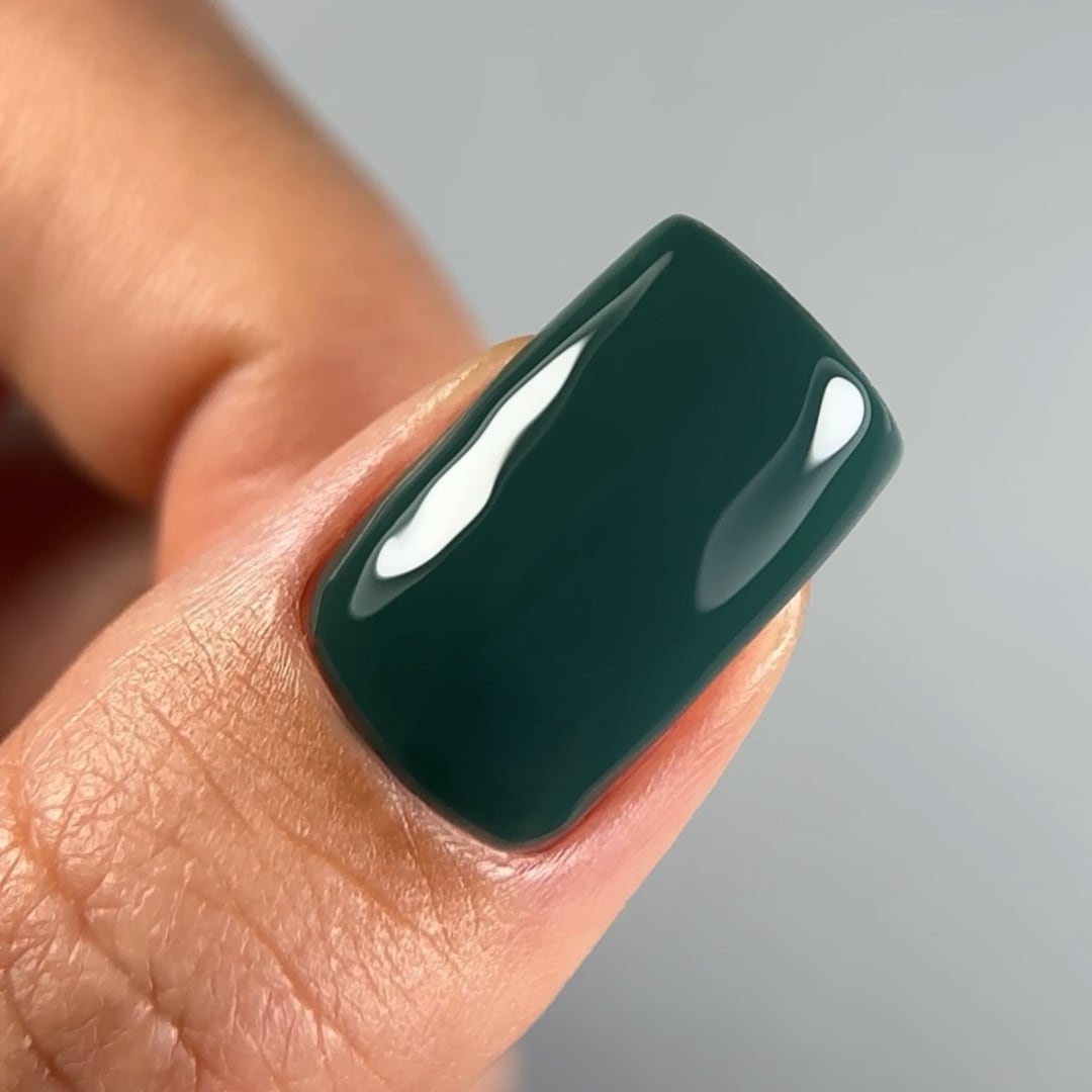 Close-up of a fingernail painted with Paloma's long-lasting gel nail polish in shade C036, a deep, highly-pigmented green. Finished with Paloma Shine Top Coat for a glossy, durable look, perfect for a sophisticated and elegant manicure.