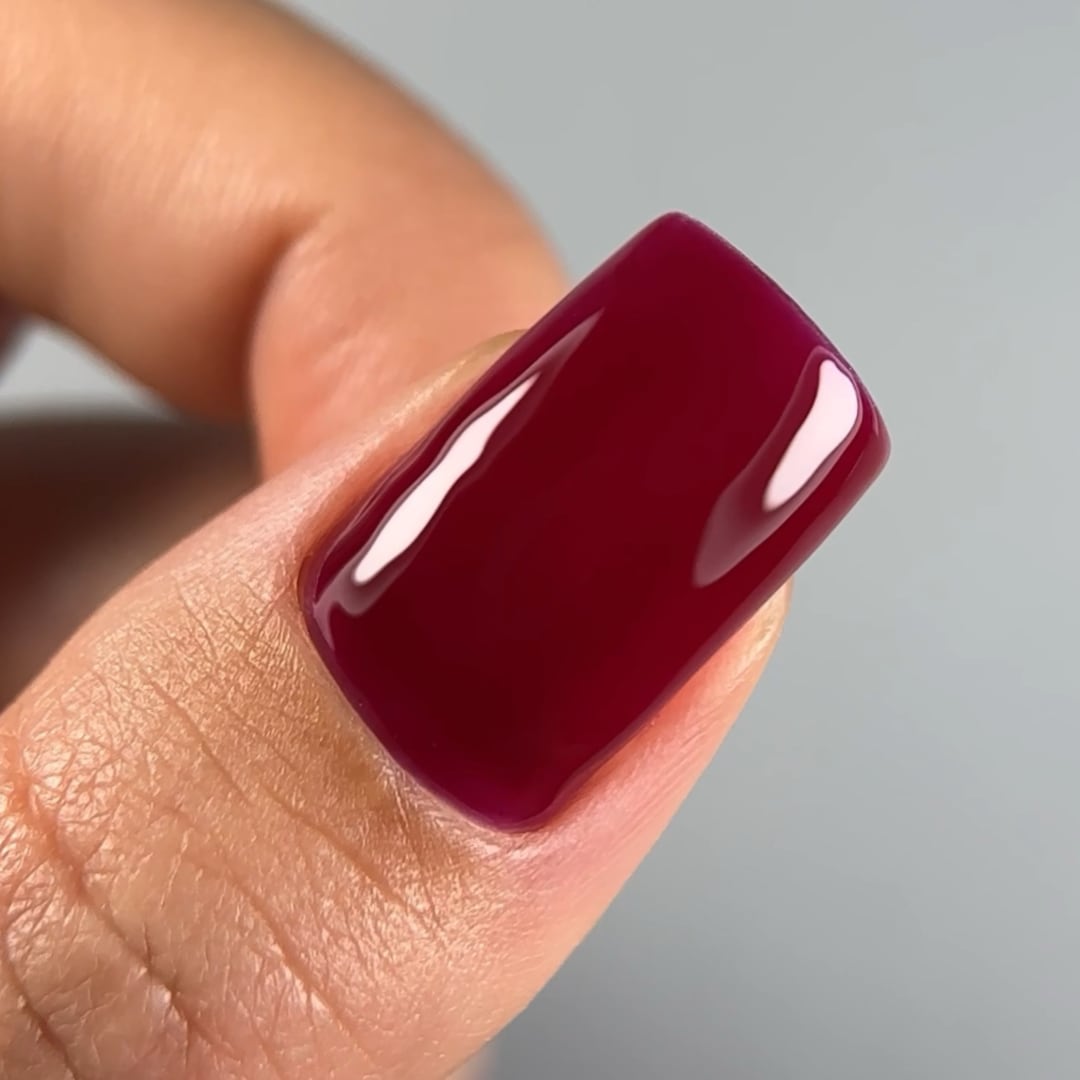 Close-up of a fingernail painted with Paloma gel nail polish in shade C059, a rich burgundy color. The glossy finish showcases the vibrant, deep red tone, perfect for an elegant and bold manicure.